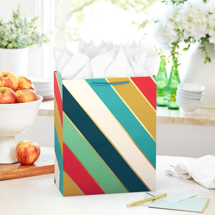 Colorful striped large gift bag with gold metallic accents and herringbone handles