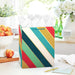 Colorful striped large gift bag with gold metallic accents and herringbone handles