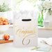 Elegant cream and gold “Congrats” gift bag styled on a tabletop with a matching celebration card
