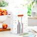 Medium birthday gift bag with colorful candles and gold glitter accents displayed on a table beside a greeting card