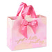 Pink and peach watercolor‑style gift bag with gold‑foil “just a little something” message and bow accent