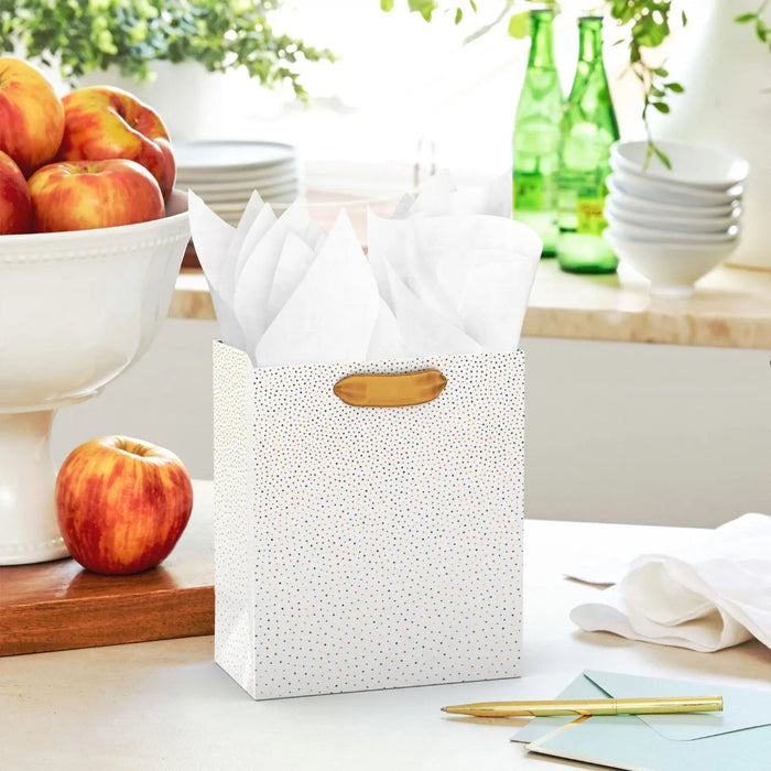 Small cream gift bag with gold foil dots displayed on a table beside a greeting card