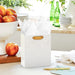 Small cream gift bag with gold foil dots displayed on a table beside a greeting card