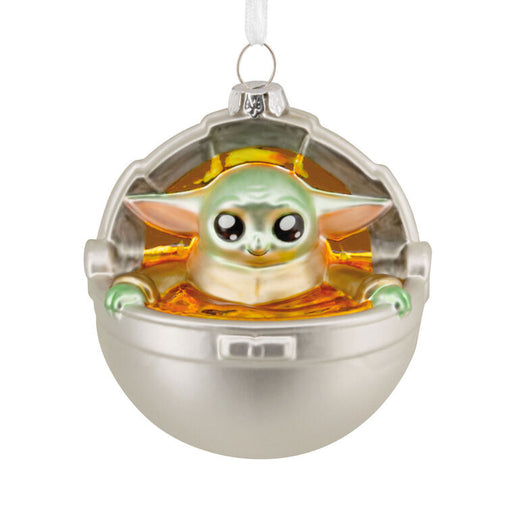 Decorative ornament featuring a character in a silver and gold pod on a white background
