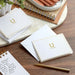 White cards with gold 'So Lucky' design on a wooden surface with stationery items.