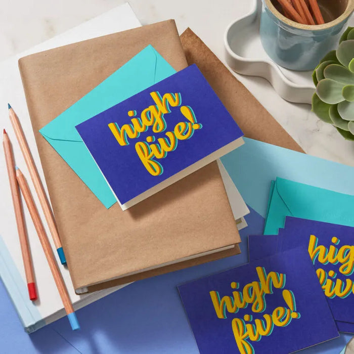 Blue cards with 'high five!' text on a desk with stationery items