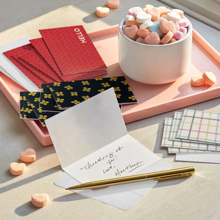 Notebooks, cards, and a pen on a surface with heart-shaped candies.