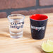 Two shot glasses with 'Patriots' branding on a wooden surface.