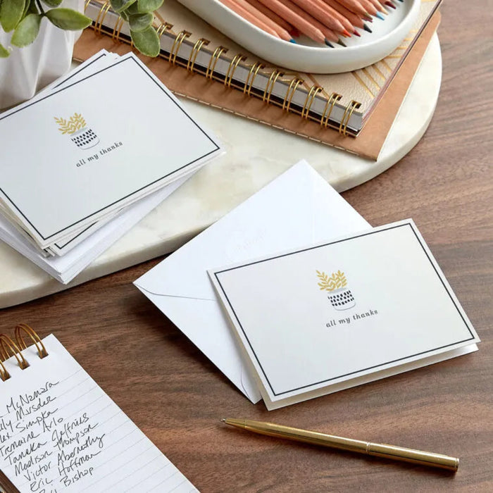 Set of stationery items including cards, envelopes, and a pen on a wooden surface.