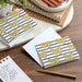 Notebooks with gold bow and black stripe design on a wooden surface with a pen.