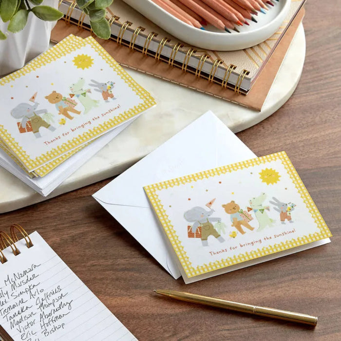 Set of greeting cards with animal illustrations on a wooden surface with stationery items.