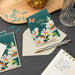 Floral greeting cards with a pen and envelope on a dark surface