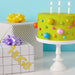 Gold foil “Hugs” hanging trim displayed on a table beside a birthday cake