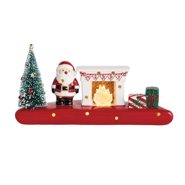Christmas-themed decorative set with Santa Claus, tree, and fireplace on a red platform.