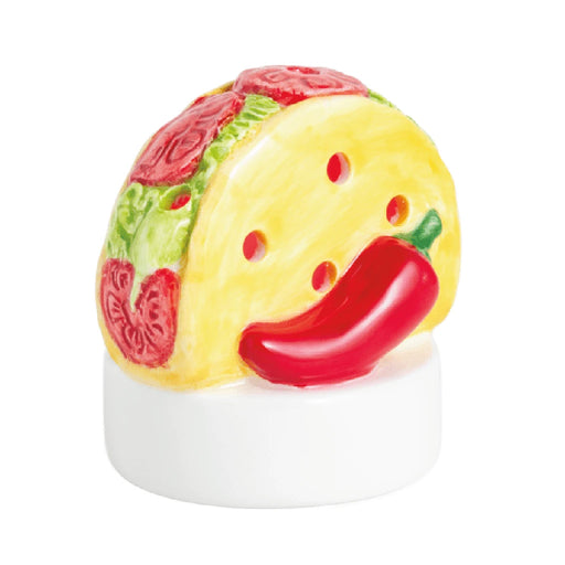 A taco-shaped candle holder beside a vibrant red pepper, showcasing a playful and colorful kitchen decor item.