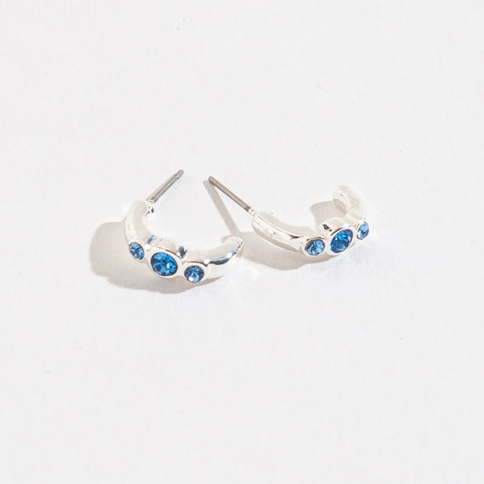 Howards Inc Blue Gem Hoop Ear Sense Earrings featuring polished silver-tone hoops with sparkling blue gemstone accents, hypoallergenic Ear Sense posts for sensitive and pierced ears, and elegant gift-ready packaging.