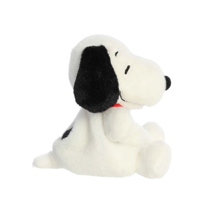 A stuffed toy dog with a bright red collar, resting on a clean white surface, emphasizing its cuddly appearance.