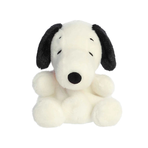 A stuffed dog with a red collar sitting on a white surface, showcasing its soft fur and playful expression.