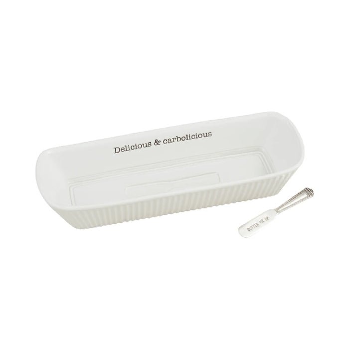 A white dish accompanied by a spoon and a knife, arranged neatly on a surface.