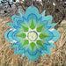 A green and blue flower made from paper cutouts, displaying a creative and colorful floral design.