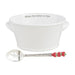 A white bowl filled with fresh strawberries beside a silver spoon on a wooden surface.