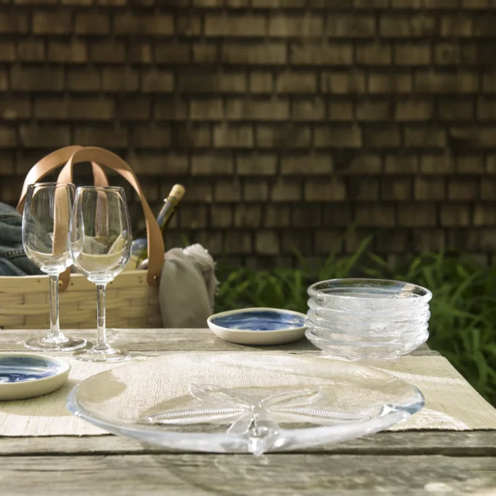 A table set with two glasses, a woven basket, and a plate, creating a cozy dining arrangement.