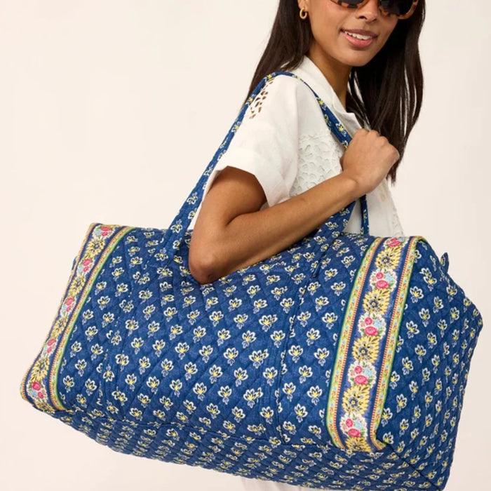 A blue duffel bag with a decorative floral print.