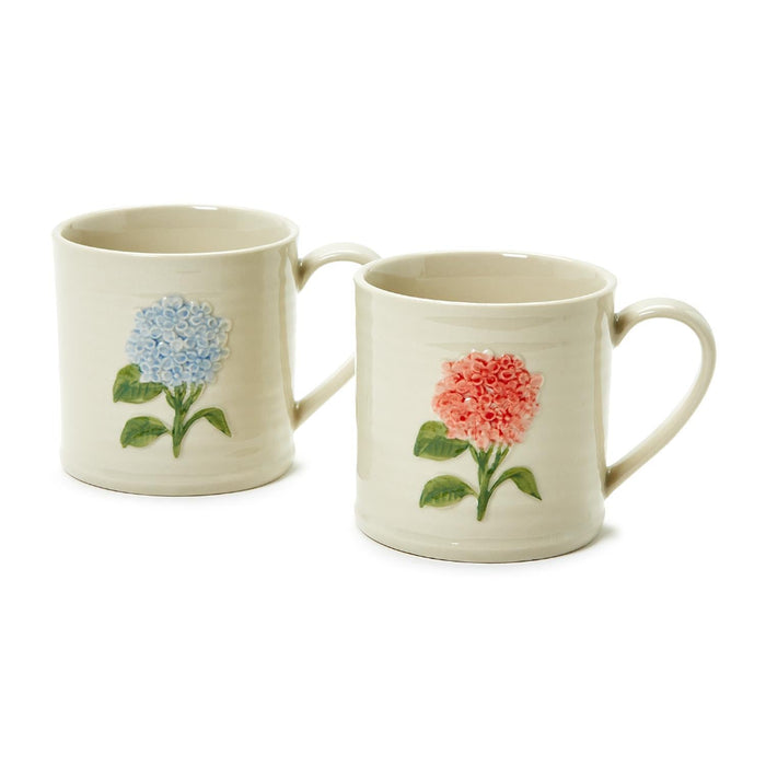 A pair of mugs featuring vibrant flower designs, positioned next to each other on a table.