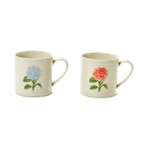 Two ceramic mugs adorned with colorful floral patterns, placed side by side on a wooden surface.
