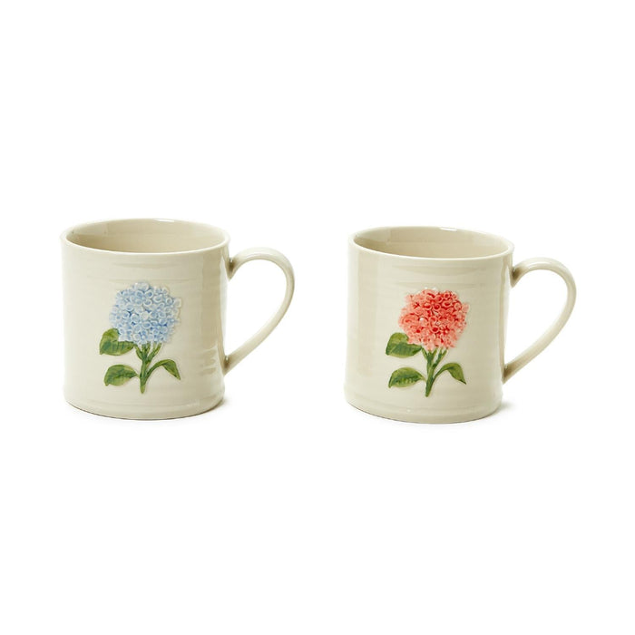 Two ceramic mugs adorned with colorful floral patterns, placed side by side on a wooden surface.