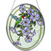 Bridgeton Hall Hummingbird Garden stained-glass-style suncatcher measuring 7 by 5.5 inches, featuring a colorful hummingbird surrounded by blooming flowers hanging in a sunny window.