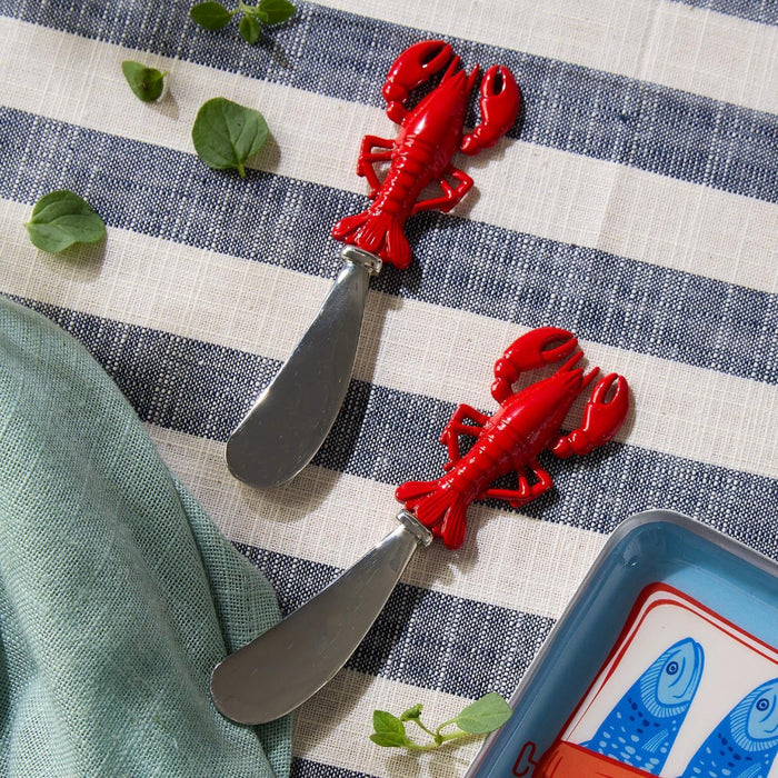 Two red lobster cutters arranged on a blue and white striped tablecloth.