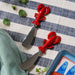 Two red lobster cutters arranged on a blue and white striped tablecloth.