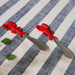 Two lobster-shaped red cutlery items are placed on a striped tablecloth, creating a whimsical dining atmosphere.