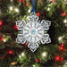 Decorative snowflake ornament with blue gem on a Christmas tree.