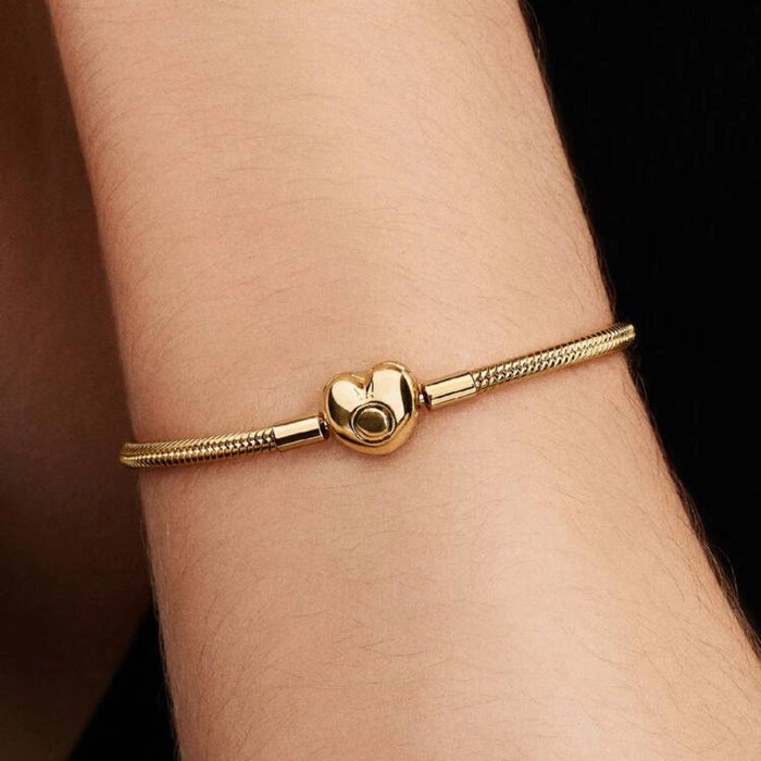 Gold-tone snake chain charm bracelet featuring a polished heart-shaped clasp on a white background, ideal for everyday wear and customizable with charms.