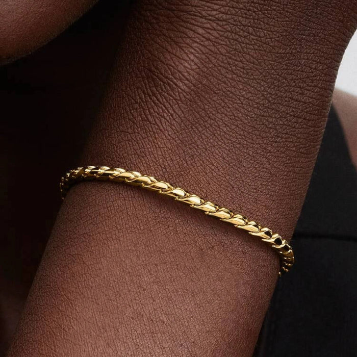 Gold-tone braided chain bracelet with a polished barrel clasp displayed on a white background, suitable for charms and everyday wear.