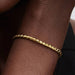 Gold-tone braided chain bracelet with a polished barrel clasp displayed on a white background, suitable for charms and everyday wear.