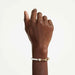 Gold-plated bracelet embellished with white pearls and a heart charm, showcasing a delicate and refined design.