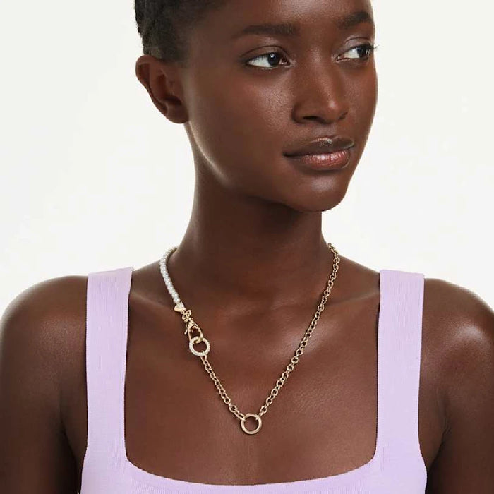 A shimmering gold chain complemented by a pearl clasp, representing timeless beauty in jewelry.