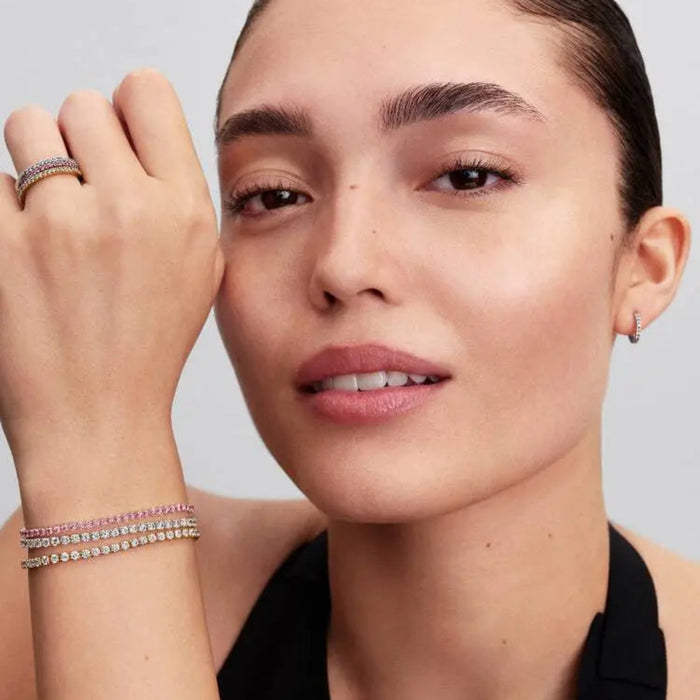 Woman wearing the Pandora Pink Small Tennis Bracelet in sterling silver, featuring a continuous row of pink cubic zirconia stones in a stack. 