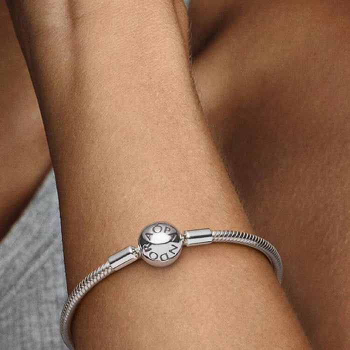 Sterling silver snake chain bracelet with a polished barrel clasp displayed on a white background, designed for everyday wear and compatible with charm beads.