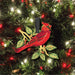 Red cardinal bird ornament on a Christmas tree with lights and decorations.