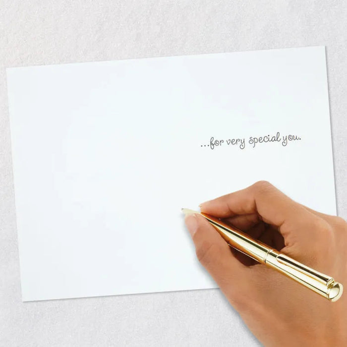 Hand holding a gold pen over a white card with text on a light gray background