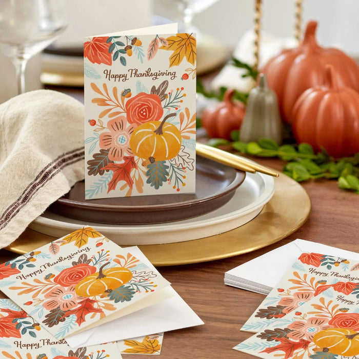 Thanksgiving greeting card featuring a harvest pumpkin, colorful autumn leaves, and floral accents for seasonal celebrations.
