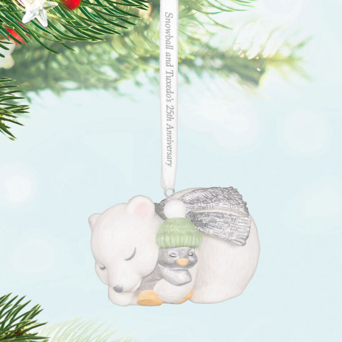 Decorative Holiday ornament with a polar bear and penguin snuggling, hanging on a Christmas Tree 