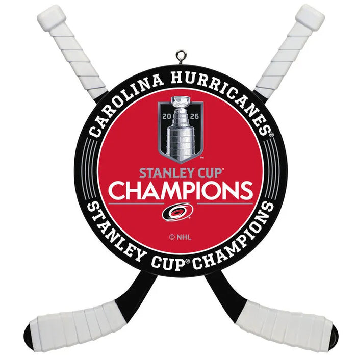 A Carolina Hurricanes Stanley Cup Champions hanging ornament shaped like hockey sticks crossed behind a circular red, black, and white center emblem featuring the Stanley Cup trophy and NHL branding.