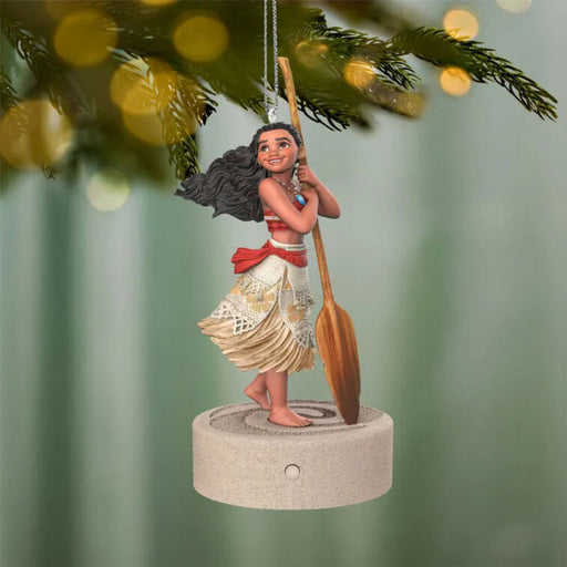 Moana Disney ornament hanging on pine tree holding wooden paddle with gold embroidery skirt