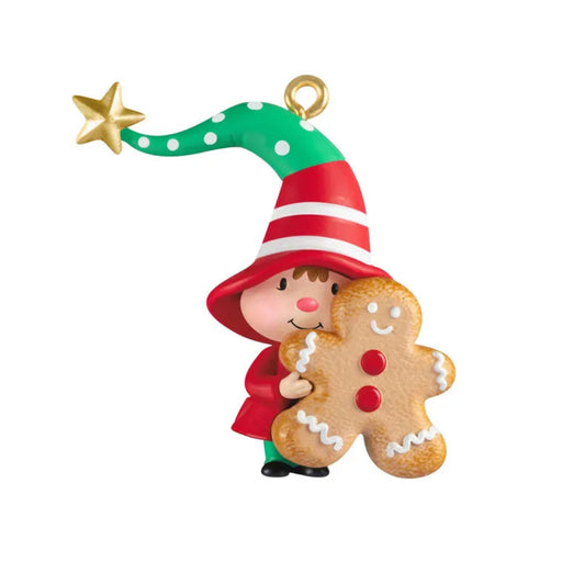 Christmas ornament of a child in a red hat holding a gingerbread man cookie on a white background