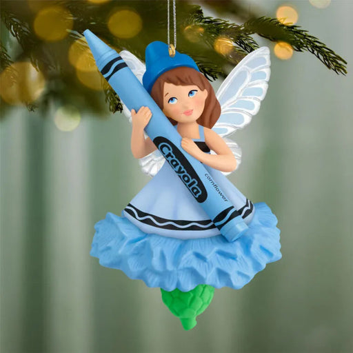 Blue Crayola fairy Christmas tree ornament hanging on pine branch with lights